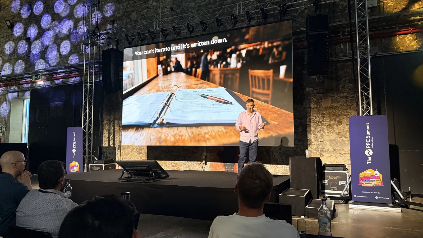 On stage at the PPC Summit 2026 in Lisbon. The slide reads: "You can't iterate until it's written down."